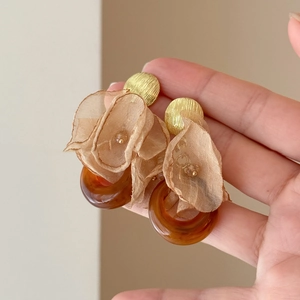 Macro shot of vintage style earrings with resin amber rings and pink chiffon flower petals