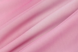 Detailed macro view of pink tie-dye mesh fabric with soft pleats and fine knit texture