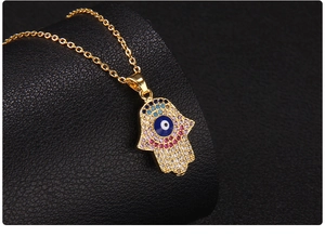 Macro shot of gold Hamsa Hand pendant with zircon Evil Eye on black leather base