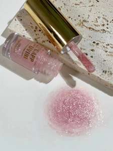 Macro shot of pink shimmer liquid eyeshadow with brush applicator on stone base