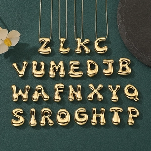 Flat lay of complete 26 golden bubble letters alphabet pendant set on dark background