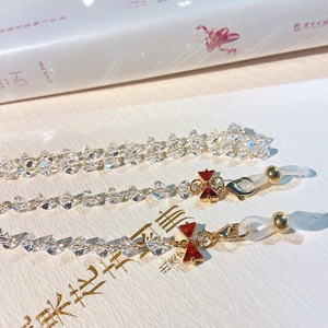 Detail of crystal eyeglass chain featuring red bow pendant and gold lobster clasp