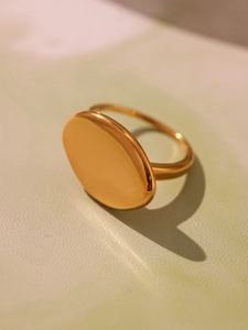 Macro shot of polished gold oval signet ring featuring a smooth surface and minimal design