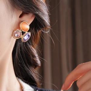 Detail view of oval vintage cat-eye earrings with colorful crystals on a model's ear