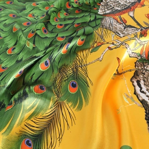 Elegant yellow silk scarf with vibrant peacock feather prints and artistic branch patterns