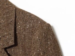Detailed macro shot of brown herringbone tweed fabric on a blazer shoulder and lapel