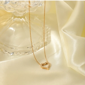 Detail of 18K gold stainless steel hollow heart pendant with zircons on silk background