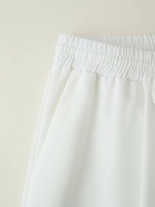 Detail of white cotton linen trousers featuring elastic waistband and mesh texture fabric