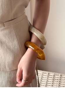 Detail view of layered amber and cream resin bracelets with thick irregular textures