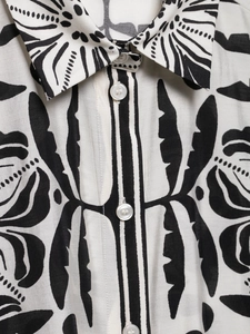 Détail du col d'une chemise ivoire à motif tropical noir montrant la patte de boutonnage et tissu