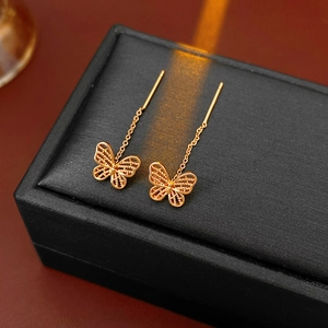 Macro detail of gold-plated butterfly long chain earrings on a black jewelry box