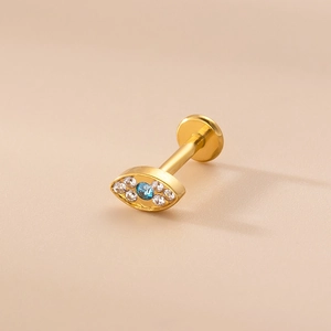 Detail of 16G gold labret stud featuring a blue cubic zirconia evil eye design