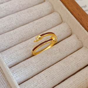 Macro detail of gold-plated nail ring with brown enamel and sparkling zircon accents