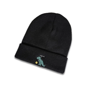 Détail d'un bonnet en maille noir avec broderie de dinosaure vert et texte