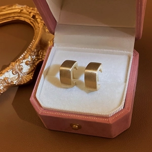 Goldene C-förmige Ohrringe in einer luxuriösen rosa Samtbox mit weichem Studiolicht