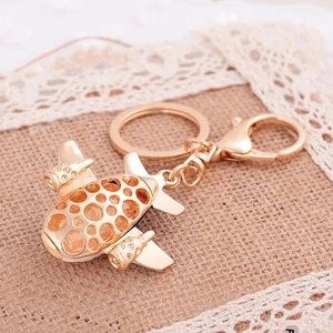 Macro shot of a golden hollow airplane keychain with crystals on vintage lace background