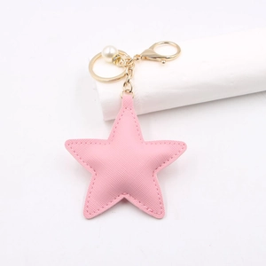 Close-up of pink PU leather star keychain with gold clasp, faux pearl and rhinestone ring