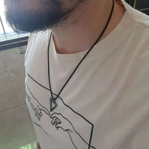 Detail of a man wearing a black cord necklace with a sleek black triangle pendant