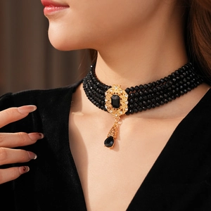 Detail view of vintage multilayer black beaded choker with golden drop gemstone pendant
