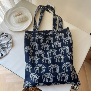 Detail of navy blue canvas tote bag with white sheep embroidery and textured finish