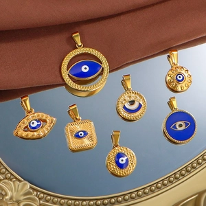 Set of seven gold evil eye charms in round and square shapes on a mirrored tray
