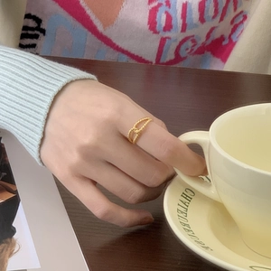 Close-up of a gold twist knot ring worn on a hand during a cozy afternoon tea setting