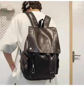 Vista posteriore del modello con zaino in pelle marrone scuro con due tasche frontali