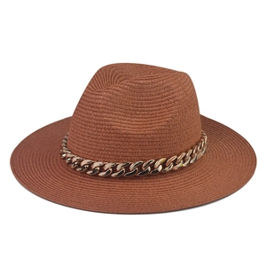 Detail of a brown woven straw boater hat featuring a stylish chunky gold chain decoration