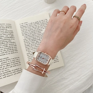 Detail of rectangular rose gold watch with white leather strap and crystal bracelet