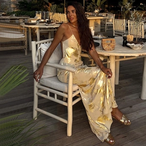 Elegant white backless halter maxi dress with gold foil leaf print on a beach terrace