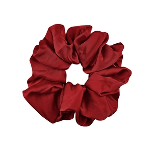 Detail of burgundy satin scrunchie with soft silk texture and elegant fabric folds