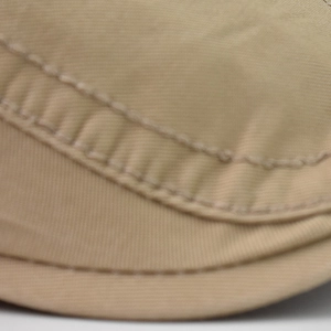 Detailed macro view of khaki cotton fabric with reinforced double stitching on the cap brim