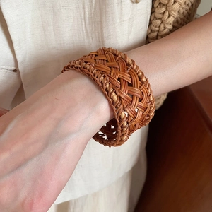 Close-up of handmade retro woven rattan bracelet in dark brown with natural plant texture