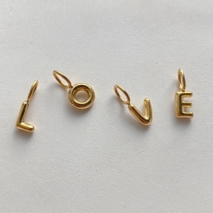 Detailed macro view of four 14K gold plated bubble letter charms spelling LOVE