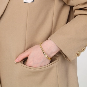 Detail of a gold stainless steel bracelet with square cubic zirconia worn by a model