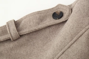 Detailed macro view of high-quality wool fabric texture and black resin buttons on coat