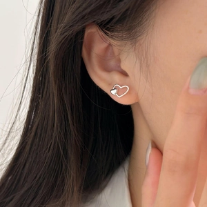 Macro detail of 925 sterling silver heart-shaped nested stud earrings on model's ear