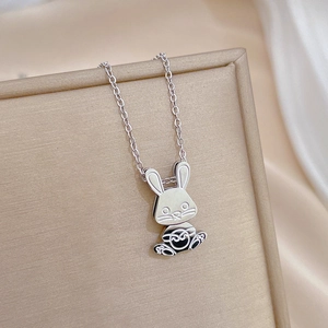 Macro shot of silver rabbit pendant with black enamel details on a luxury silk backdrop