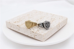Close-up of vintage shield rings in gold and silver with ornate cross and vine engravings
