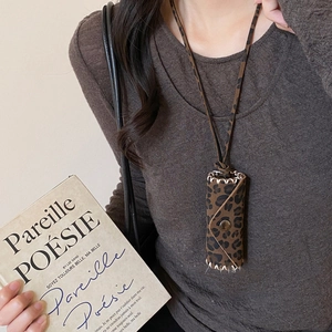 Close-up of leopard print mini bag pendant with white hand-stitched seams and gold metal snap