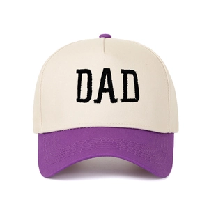 Detail der DAD-Stickerei auf einer zweifarbigen beige-violetten Trucker-Baseballkappe