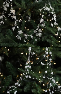 Close-up of sparkling Christmas snowflakes and pearl bead garland on green pine branches