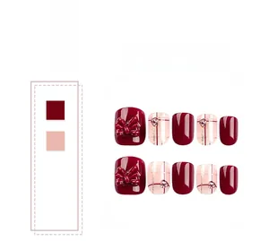 Detail of red press-on nails featuring 3D bows, pink rhinestones, and gold glitter patterns