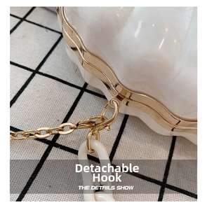 Detail of detachable gold metal and white resin chain link on marble acrylic clutch