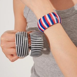 Close-up of wide striped resin bangles in red, white, blue and black color patterns