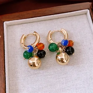 Boucles d'oreilles créoles dorées avec perles de pierre colorées dans un écrin de luxe