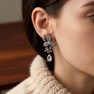 Orecchini vintage a fiore con zirconi e pendente a goccia indossati da una modella