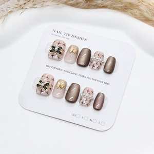 Macro view of handmade cat-eye nails with brown glitter, pink plaid, and 3D bows