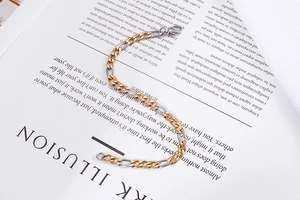 Close-up of gold and silver cuban link chain bracelet with lobster clasp on magazine