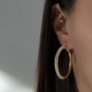 Chic gold hoop earring with small sparkling rhinestones on model with minimalist ear stud